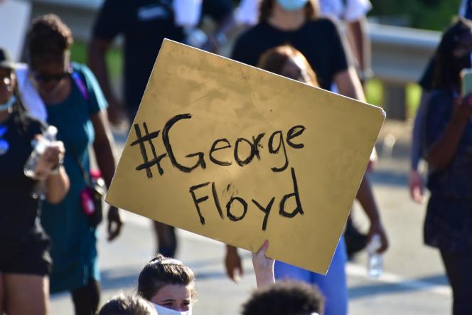 A protester holding up a yellow board that says George Floyd