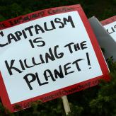 A red and white sign that says "capitalism is killing the planet!"