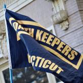 A black flag with the Oath Keepers logo in yellow printed on it.