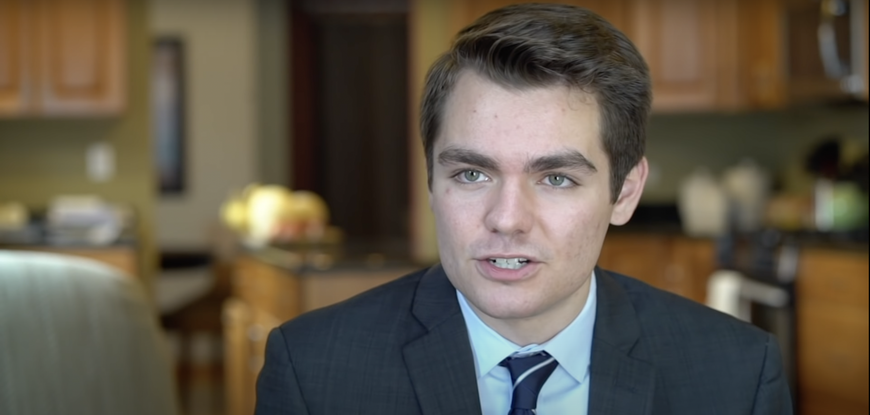 A young white man, Nick Fuentes, in a suit
