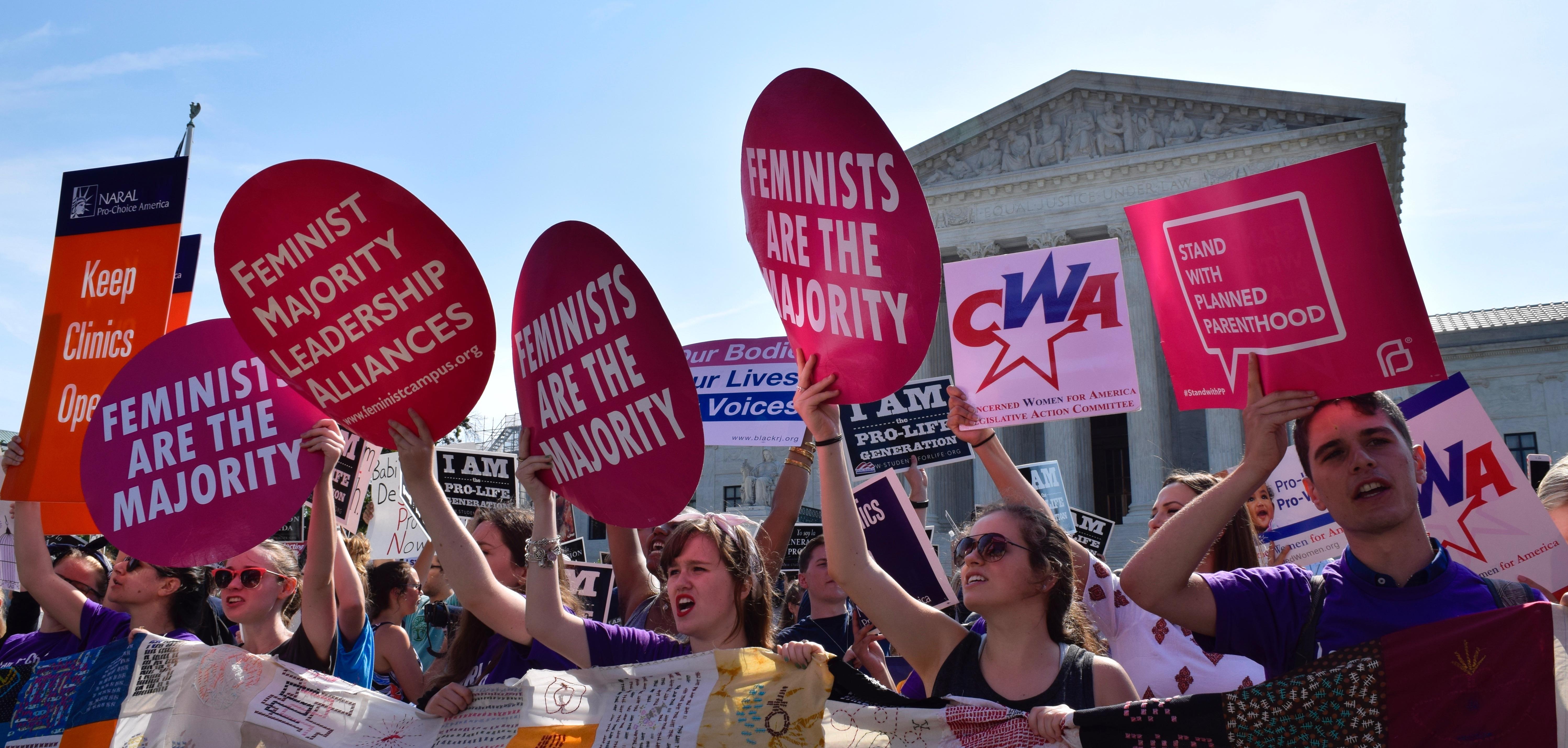 Women holding up signs that say "Feminist majority leadership alliances" in front of the Supreme Court