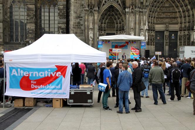 A tent with the AfD logo on one side. People are standing in front of the tent.