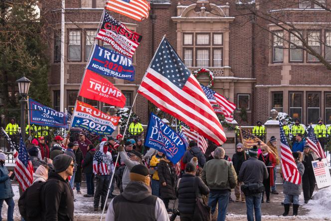 A group of people gathered holding many Trump flags