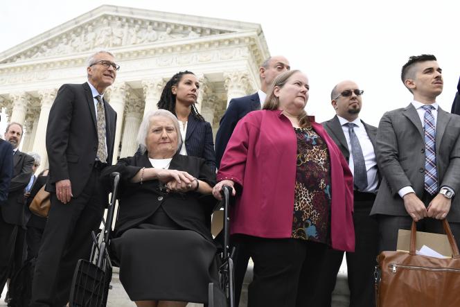 Aimee Stephens, seated, and her wife Donna Stephens, in pink, listen during a news conference outside the Supreme Court in Washington