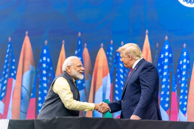 Trump and Modi shaking hands in front of Indian and American flags.