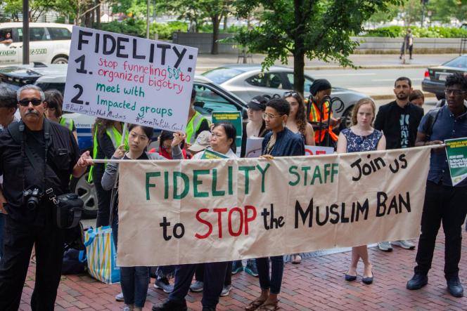A group of people holding signs. One sign says "Fidelity Staff Join us to Stop the Muslim Ban."
