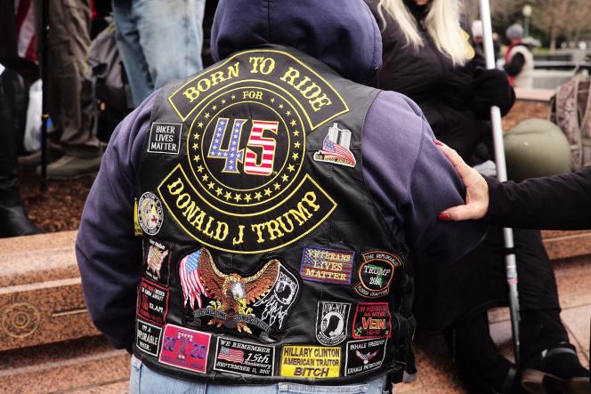A person wearing a black leather jacket with various patches.