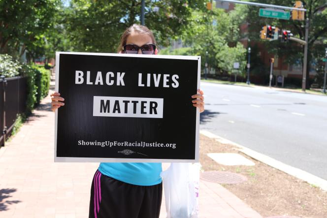 A woman holding a sign that says "Black Lives Matter"