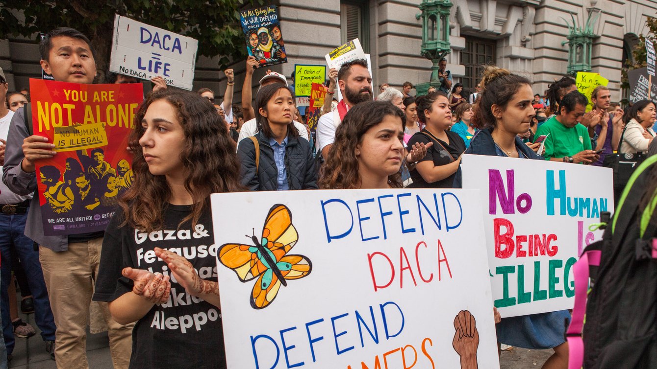 Protesters hold various signs and banners at a DACA rally in San Francisco.