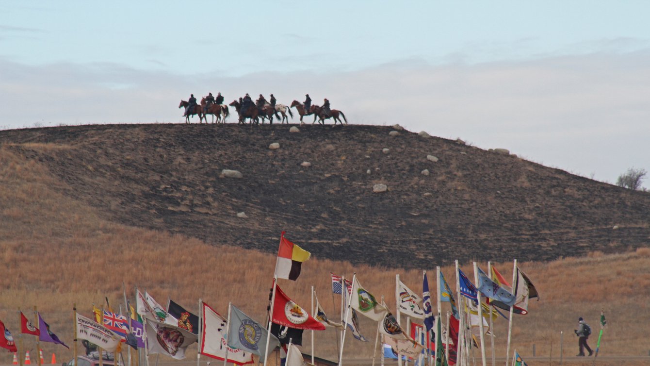 Riders on horseback overlook Oceti Sakowin Camp occupied by Standing Rock protesters.