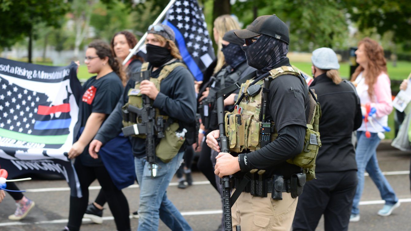 Armed militia members march next to a WWG1WGA flag, a common identifier of QAnon believers, at the United We Stand & Patriots March for America, St. Paul, Minnesota, September 12, 2020 (Credit: Fibonacci Blue/Flickr).