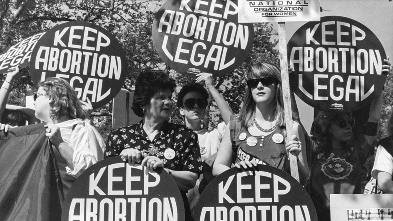 White women protesting, holding circular signs that say "Keep Abortion Legal"