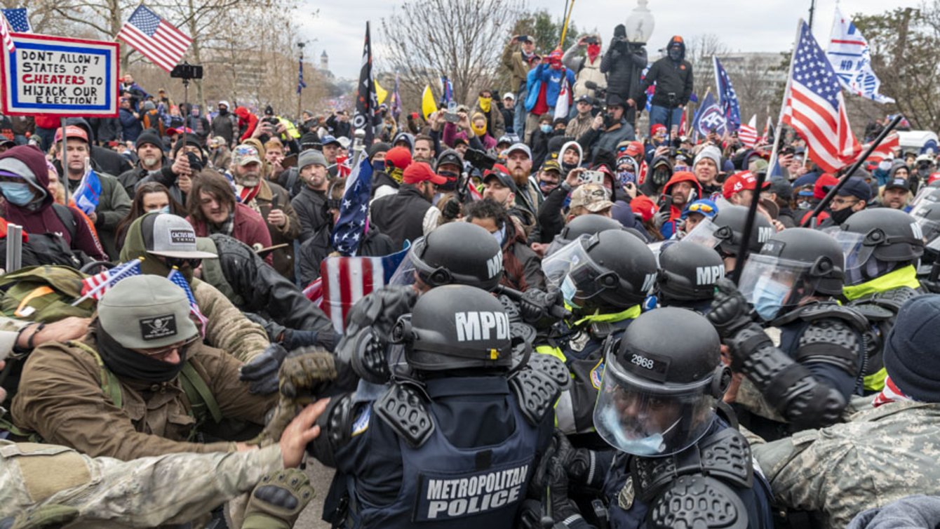 insurrectionists clashing with police on January 6th. Men are pushing against each other.