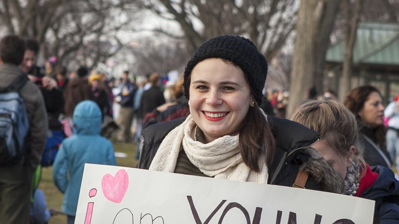 A white woman holding a sign saying "I am young, I am a woman, I am FOR life"