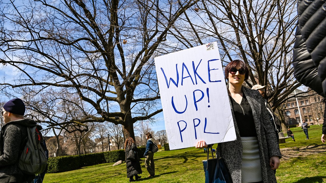 A woman holding a sign saying "Wake up! Ppl"