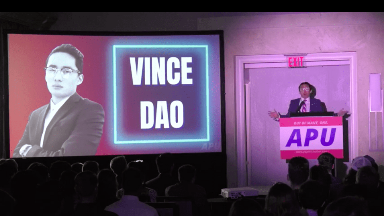 Man standing on stage next to Powerpoint that reads "Vince Dao"