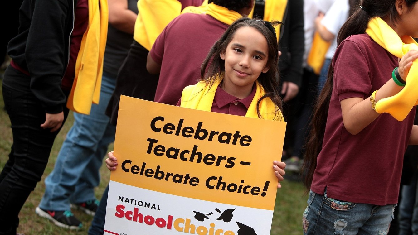 A young girl holding a sign that says Celebrate Teachers - Celebrate Choice! National School Choice Week