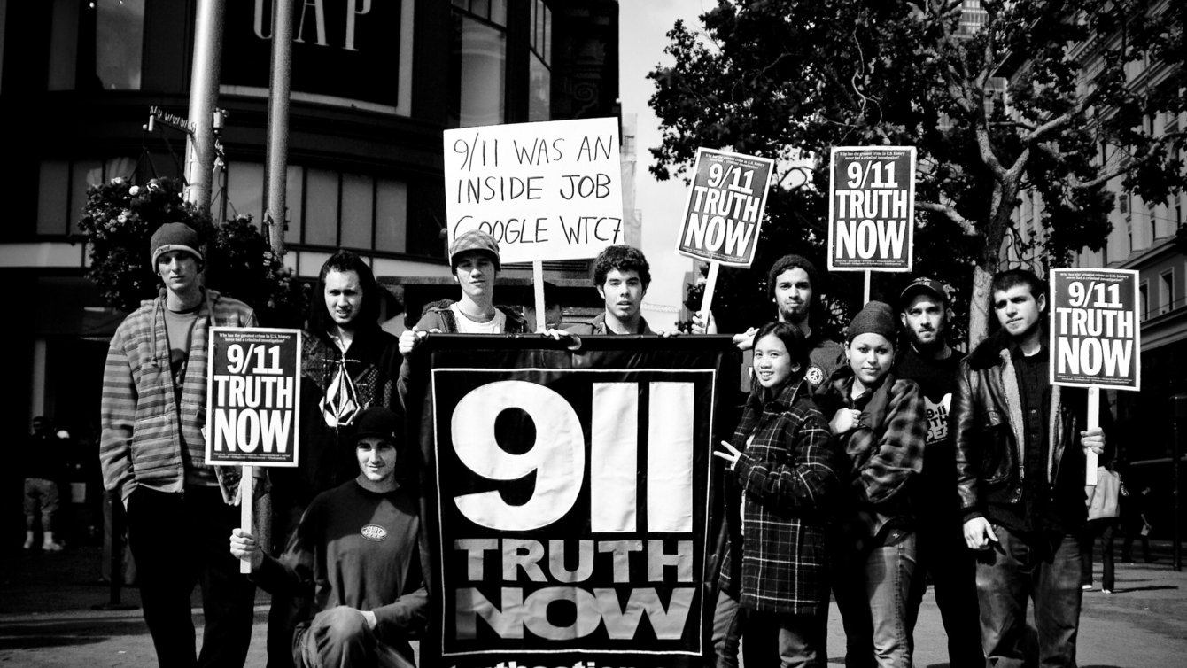 A group photo in BW of protestors holding signs that read 911 Truth Now
