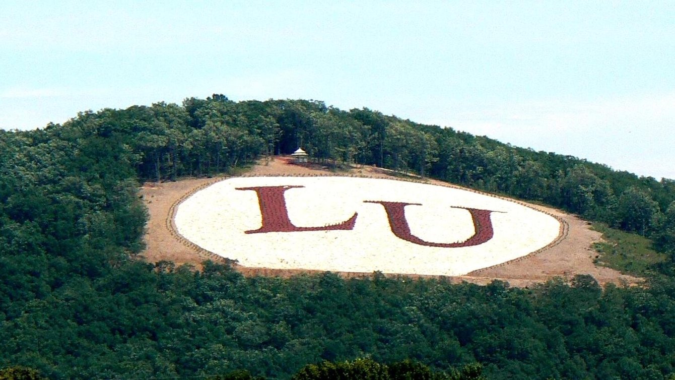 The letters LU in red on a green mountain