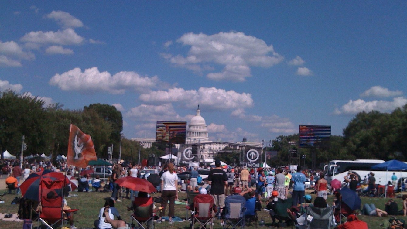 People standing in a field sporadically in front of the D.C capitol