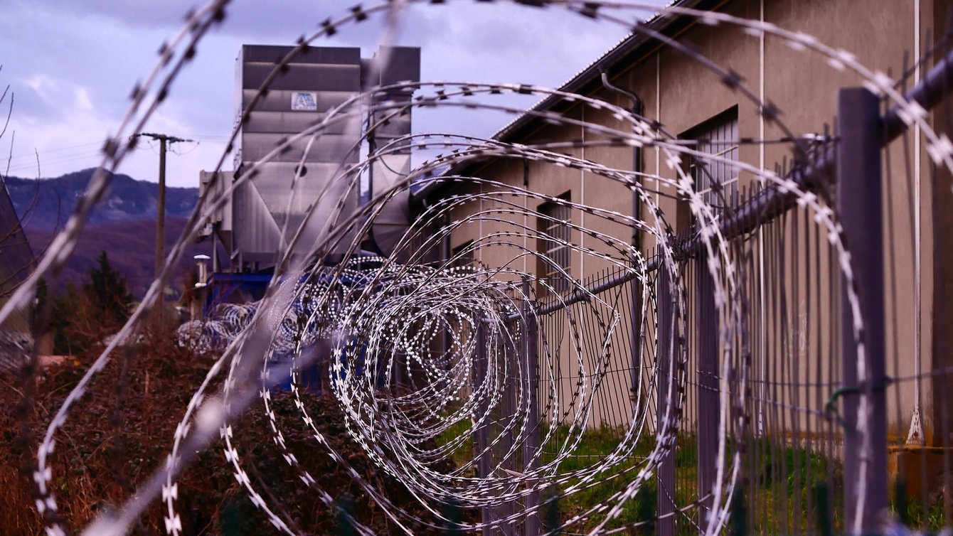 Barbed wire in a spiral form outside a brown building.