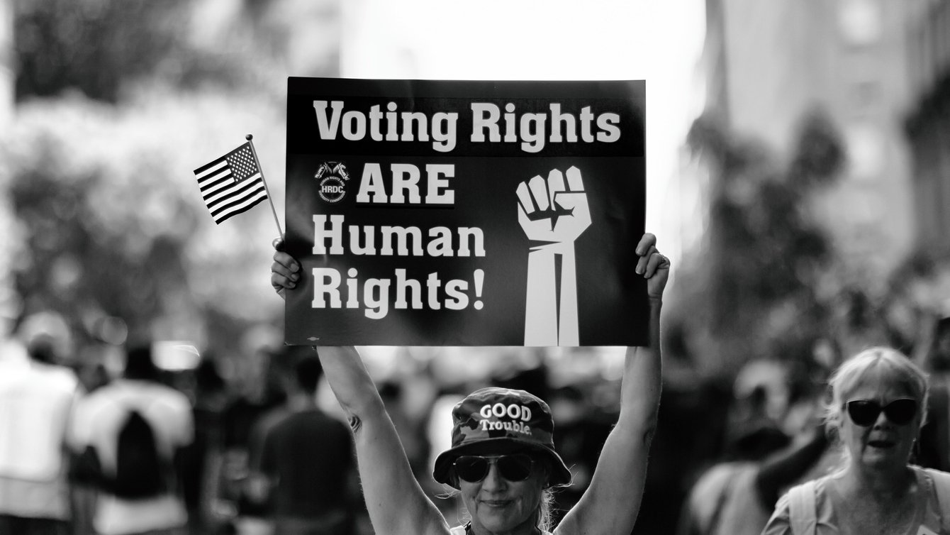 A person holding a banner saying "voting right are human rights!"