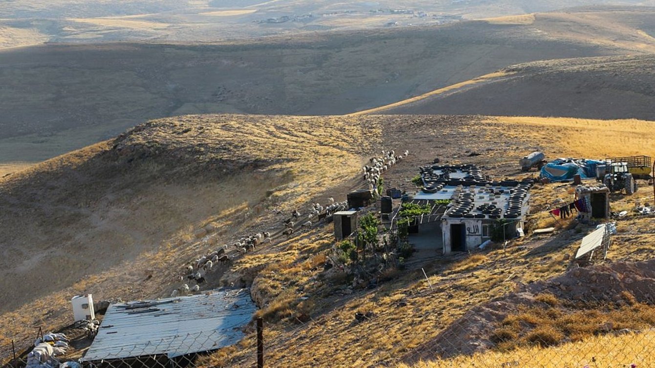 Hills and dunes surrounding houses with tin roofs.