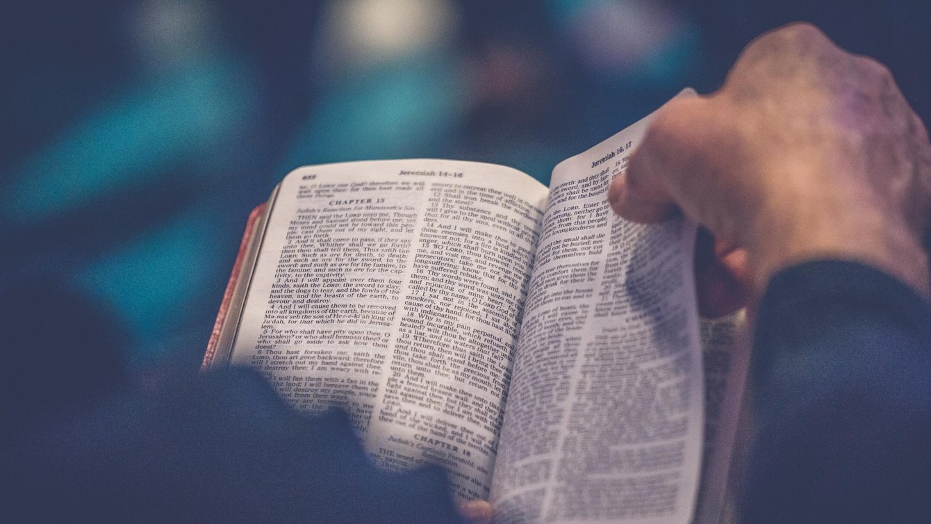 Person's hand turning a page of a Bible.