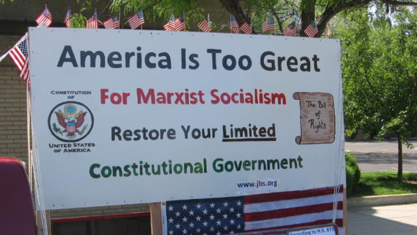 A sign that says "America is too great for marxist socialism. Restore your limited. Constitutional Government. www.jbs.org"
