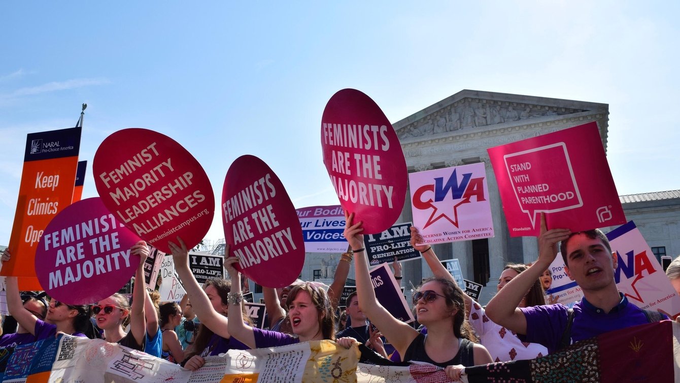 Women holding up signs that say "Feminist majority leadership alliances" in front of the Supreme Court