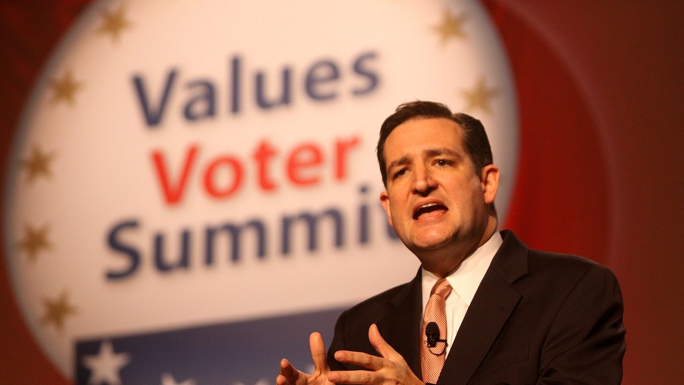 A man in the middle of a speech in a suit with "Values Voter Summit" in the background.