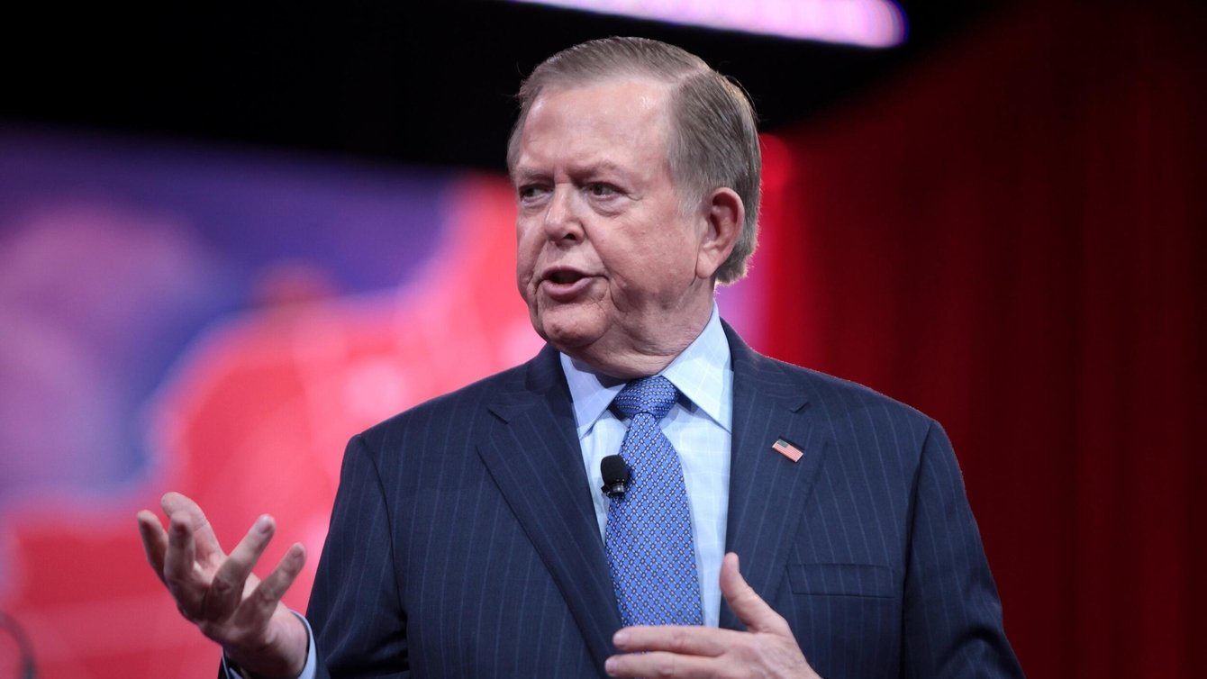 A man in a blue suit, speaking.
