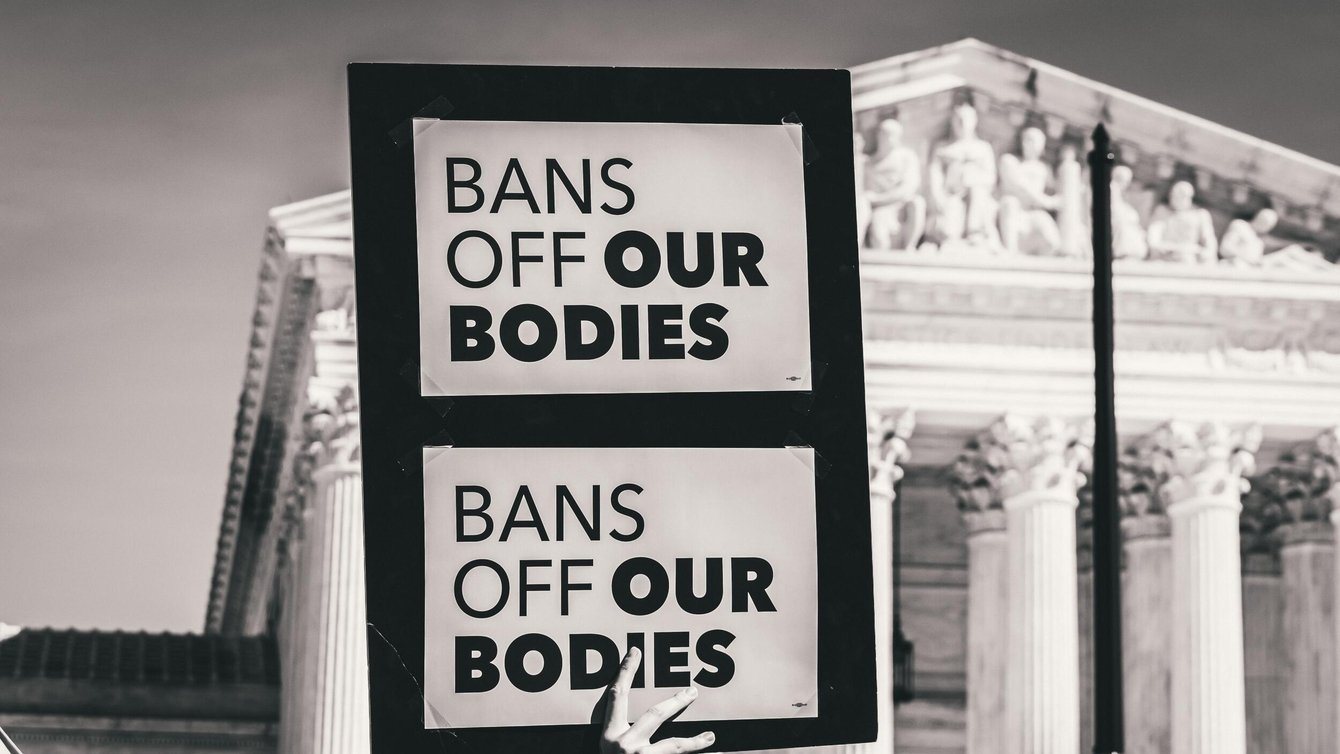 A protestor holding a paper that says "Bans of our bodies"