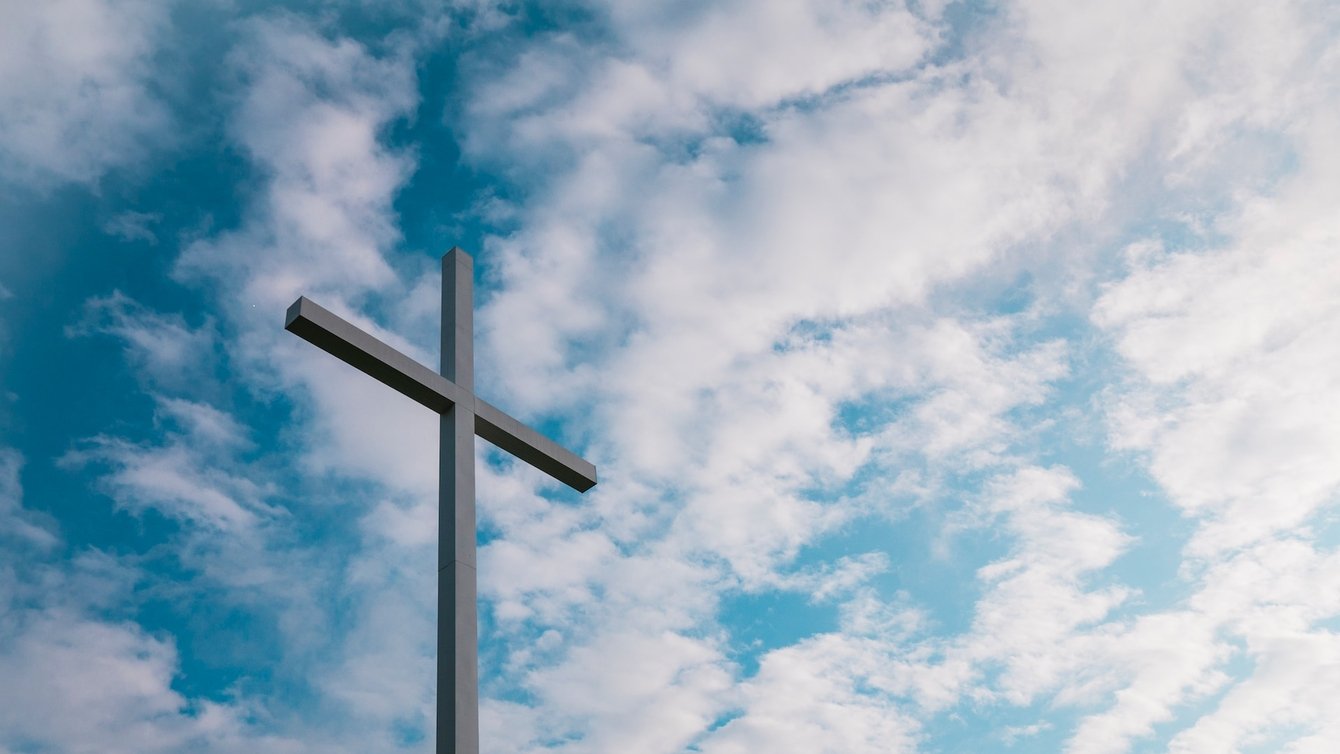 a cross with clouds in the background.