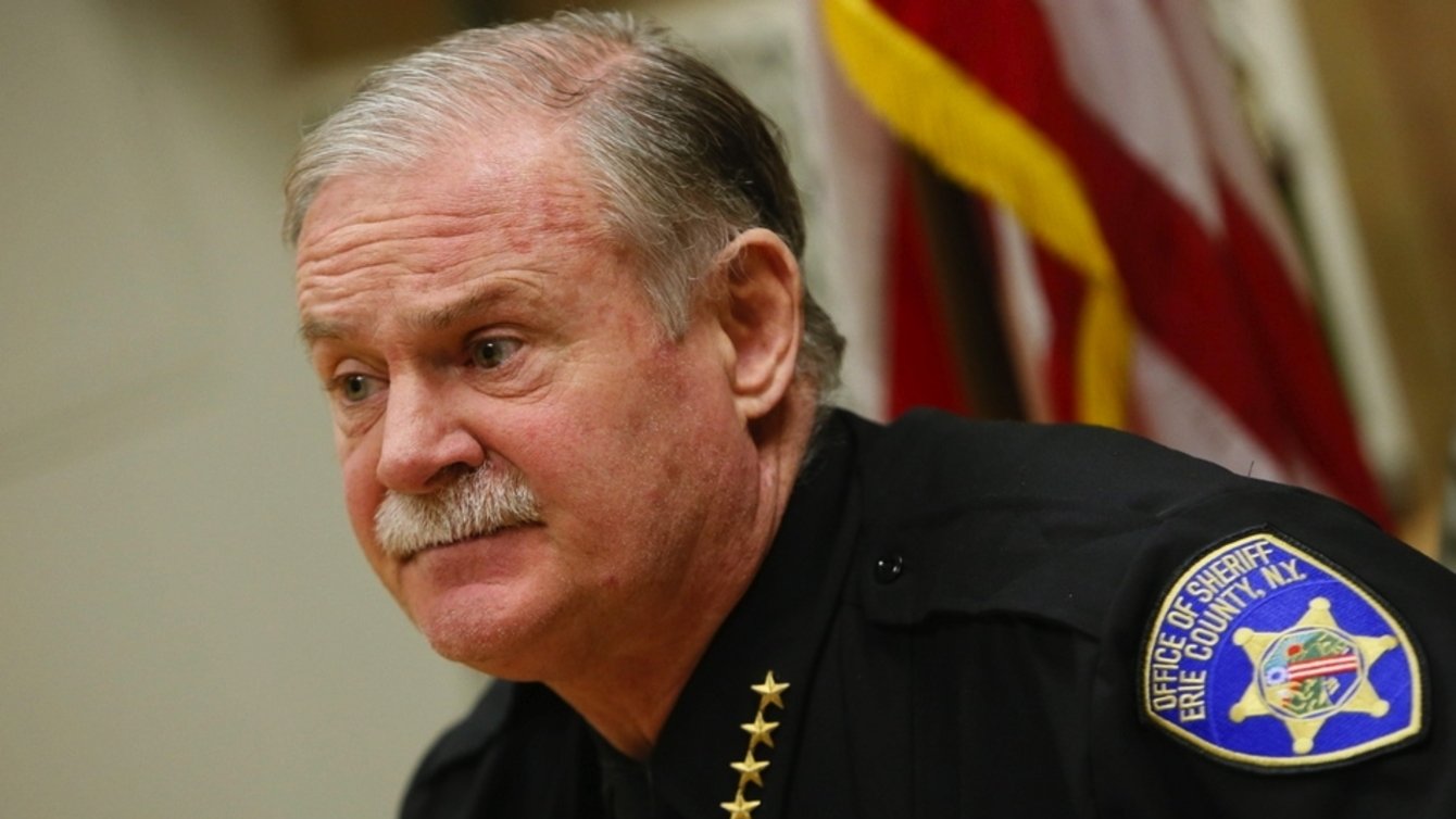 A man with white hair and white mustache in a sheriff's uniform.