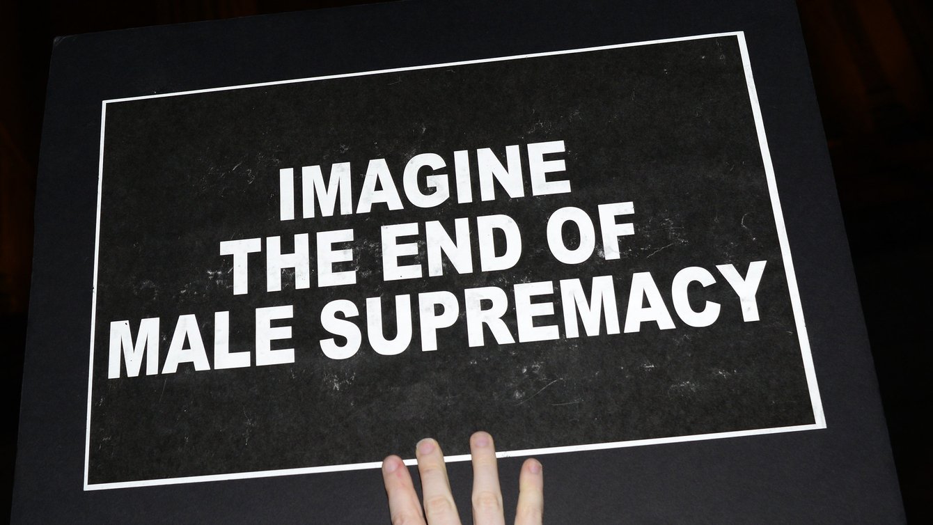 A black sign with the words "imagine the end of male supremacy"