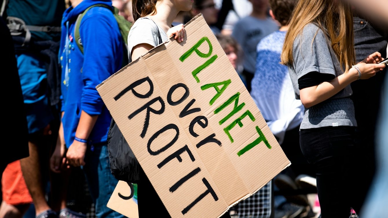 A sign at a protest saying "planet over profit"