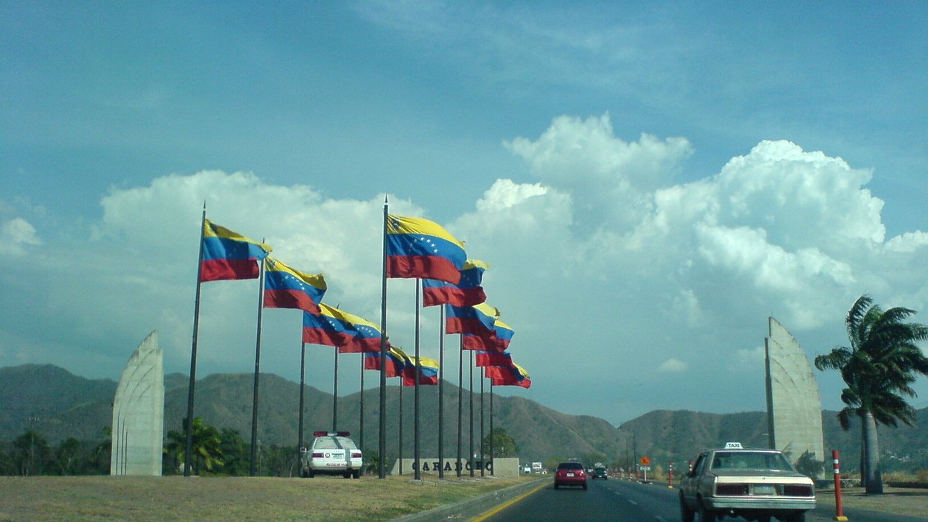 Venezuelan flags along a road with cars on it