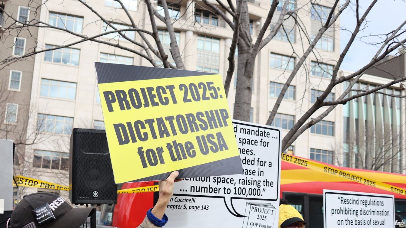 Hand holds a sign reading "project 2025: dictatorship for the USA"