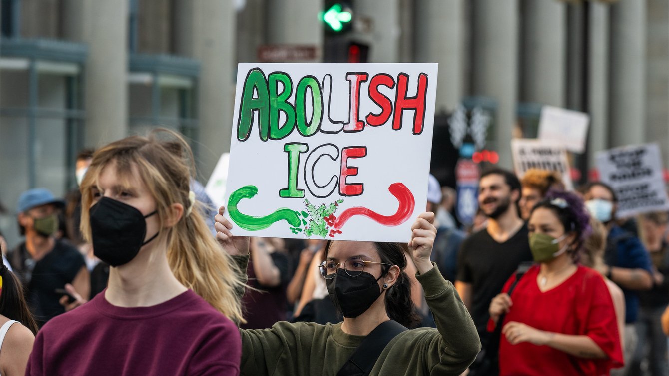 A protester holding a sign that reads "Abolish ICE"