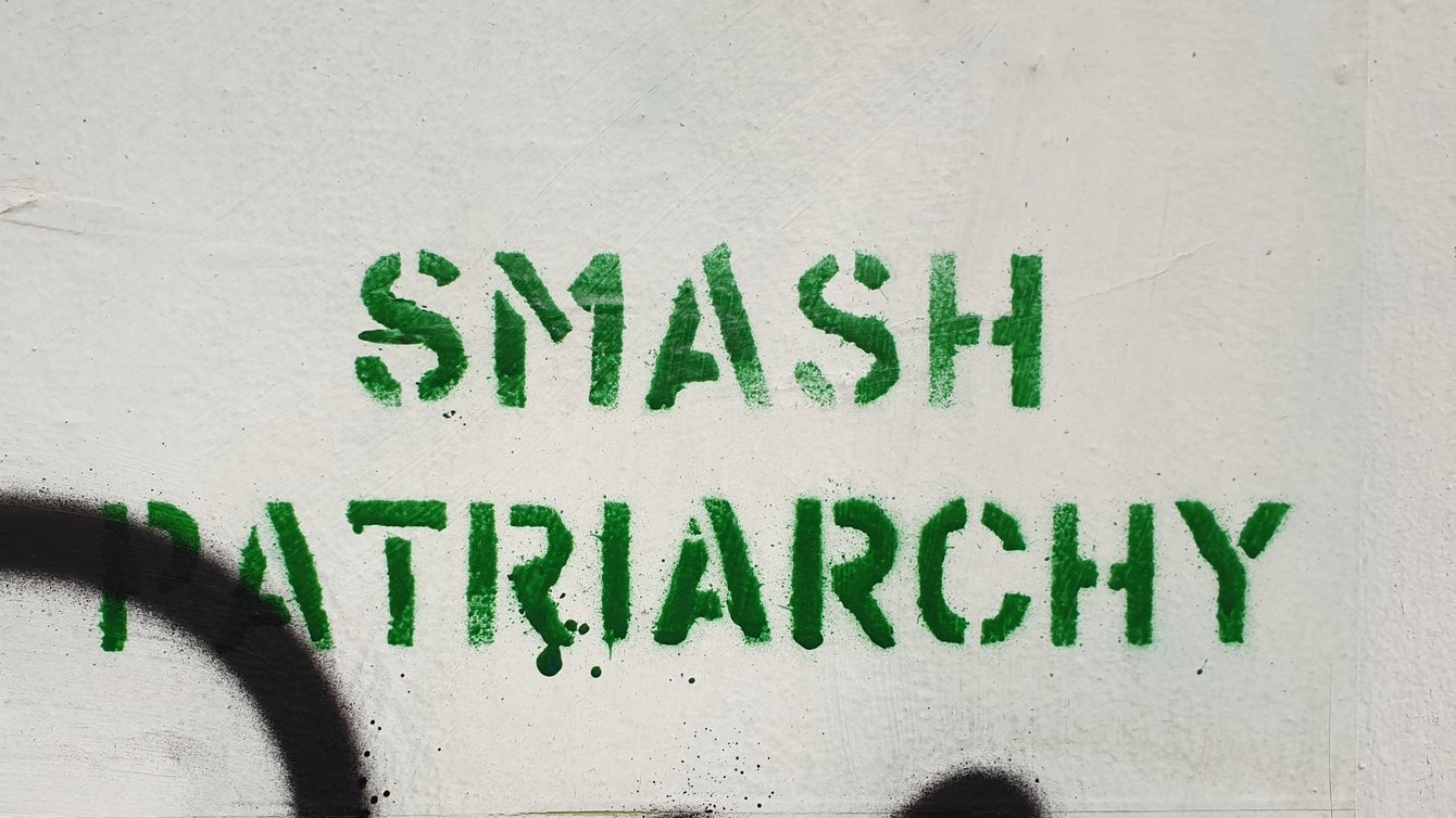 A beige wall with the words "smash patriarchy" graffitied in green on it.