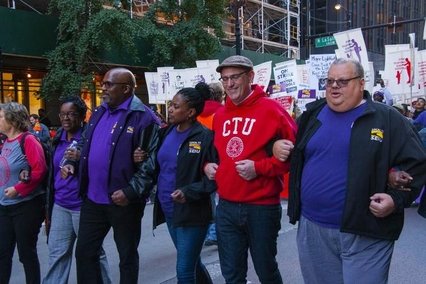 Six people linking arms and walking down the street. One man is wearing a red sweatshirt that reads CTU