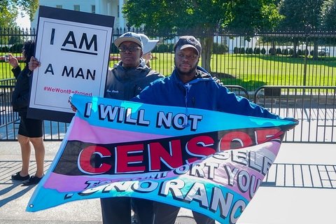 Two protesters hold signs at a rally for trans rights