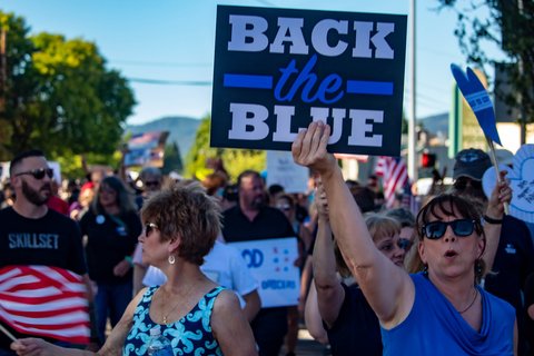 Protesters gathered. A woman holds up a sign that read Back the Blue.