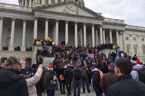 A group of right wing protesters outside the Capitol building in Washington DC. They are climbing the Stairs of the building.