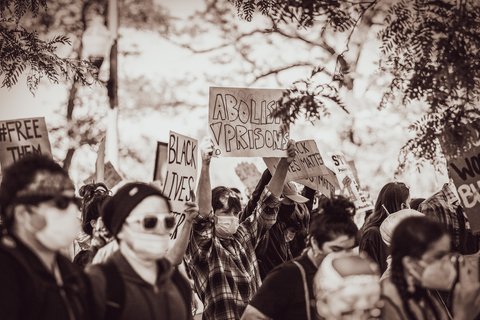 A person at a protest holding a board that says "Abolish Prisons"
