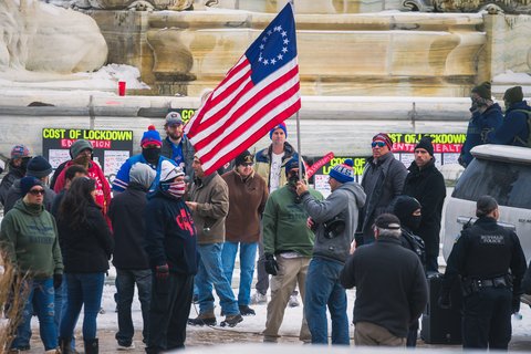 Crowd wearing winter clothes holding colonial American flag