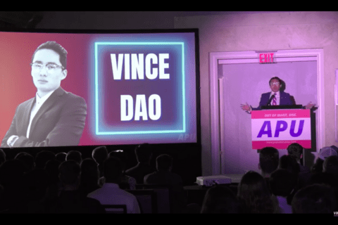 Man standing on stage next to Powerpoint that reads "Vince Dao"