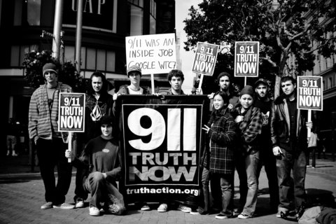 A group photo in BW of protestors holding signs that read 911 Truth Now