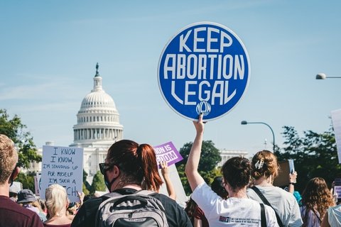 A protester in front of the Capitol holding a sign that says "Keep Abortion Legal"